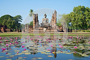 Ruins of ancient Buddhist temple Wat Chana Songkram on the shore of a lake with pink lilies. Sukhothai, Thailand