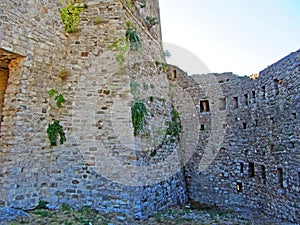 The ruins of an ancient fortress. old thick stone walls of a European fortress overgrown with greenery in the mountains. Doors and