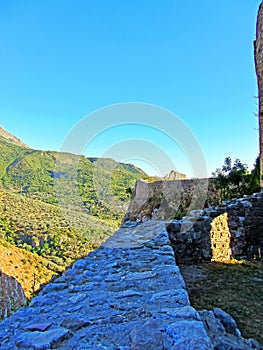 The ruins of an ancient fortress. old thick stone walls of a European fortress overgrown with greenery in the mountains. Doors and