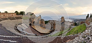 Ruins of ancient Greek theater in Taormina and Etna volcano in the background. Coast of Giardini-Naxos bay, Sicily, Italy, Europe
