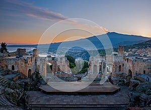 Ruins of Ancient Greek theatre in Taormina on background of Etna Volcano, Italy. Taormina located in Metropolitan City