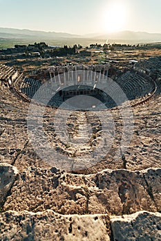 Ruins of ancient Hierapolis Amphi theatre with tourist Pamukkale, Denizili, Turkey. Evening sun