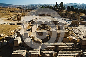 Ruins with building blocks sanctuary of Zeus Olympios and Oval Forum antique town Gerasa. Modern Jerash on background.Tourist