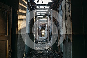 Ruins of burned brick house after fire disaster accident. Corridor inside, building without roof, heaps of ashes