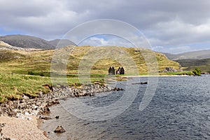 Ruins of Calda House against the Scottish Highlands, rugged hills and serene lake reflections photo