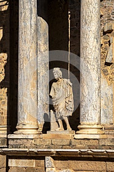 Ruins of classical statue with toga and Greek and Roman columns of the Roman Theater of Merida in Extremadura, illuminated by the