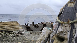 Ruins of fishing boats and garbage on seashore. Clip. Garbage and ruins of sea boats on shore on cloudy day. Debris and