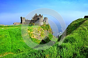 Ruins of the medieval Dunluce Castle along green cliffs, Causeway Coast, Northern Ireland