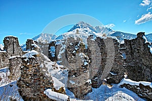 Historic ruins on mountain top in alpine landscape by blue sky in winter