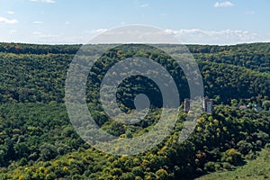 Ruins of the old castle on the hill hugged by autumn forest.