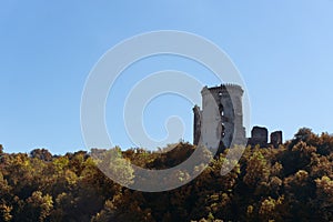 Ruins of the old castle on the hill hugged by autumn forest.