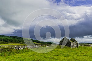 Ruins of old Irish cottage with stone walls surrounded by the countryside