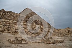 Ruins of the small pyramid of Queen Henutsen with Cheops Pyramid at background, Giza Plateau, Egypt. UNESCO World Heritage