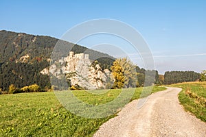 Ruins of Strecno castle in autumn landscape with dirt road