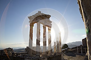 Ruins of the Temple of Trajan the ancient site of Pergamon. Izmir, Turkey. Ancient city columns with the sun in the background.