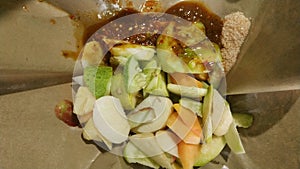 Rujak buah or indonesian mixed fruit salad, served with spicy brown sugar sauce and ground peanuts photo