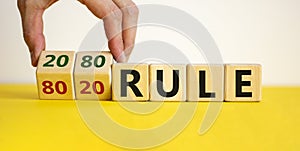 80 on 20 rule symbol. Male hand flips wooden cubes with words `80 on 20 rule`. Beautiful yellow table, white background, copy