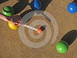 A ruler in inches measures the outcome of a game of bocce.