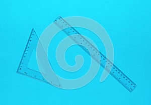 Ruler and triangle made of transparent plastic on a blue background