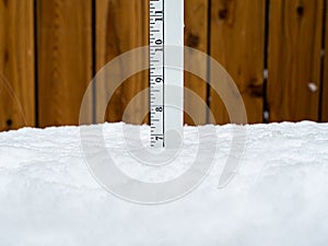Ruler or yardstick stuck in snow measuring the snow depth of 7 inches.