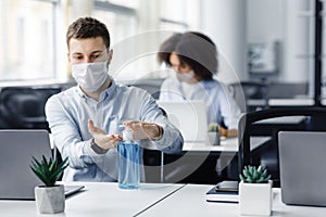 Rules for safety health during coronavirus outbreak. Man in protective mask treat his hands with antiseptic at workplace