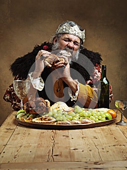 Ruling is hungry business. A mature king feasting alone in a banquet hall.