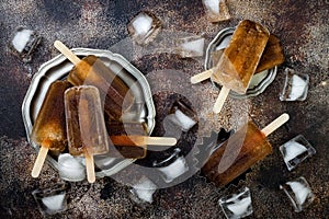 Rum and coke cocktail popsicles with lime juice. Cuba libre homemade frozen alcoholic paletas - ice pops. Overhead, flat lay