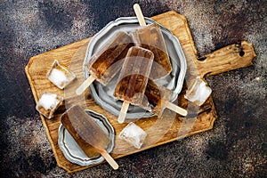Rum and coke cocktail popsicles with lime juice. Cuba libre homemade frozen alcoholic paletas - ice pops. Overhead, flat lay photo