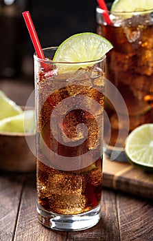 Rum and cola cocktail with lime slice in tall glasses