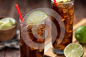 Rum and cola cocktail with lime slice in tall glasses