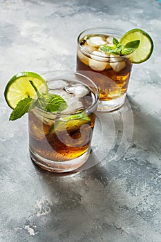 Rum and cola. Cuba Libre drink with lime and ice on rustic concrete table