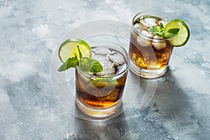 Rum and cola. Cuba Libre drink with lime and ice on rustic concrete table