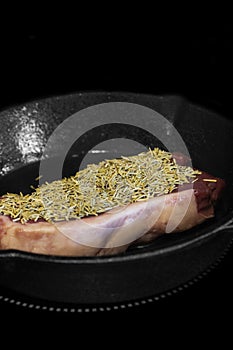 Rump beef steak covered in rosemary cooking on an electric hob stove.