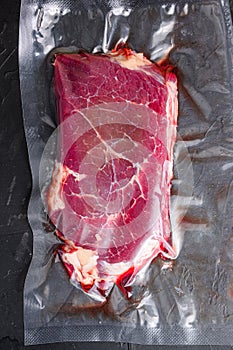 Rump beef steak for sous vide cooking on black stone background, top view