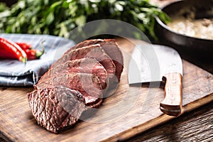 Rump steak cut to slices on a chopping board next to a knife