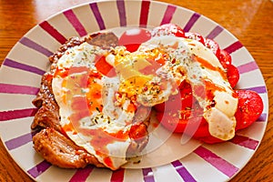 Rump steak and fried eggs with fresh tomato