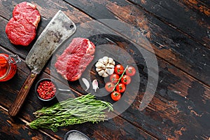 Rump steak, raw marbled beef steak, with old butcher knife cleaver, and seasonings  On dark wooden rustic table,  top view with