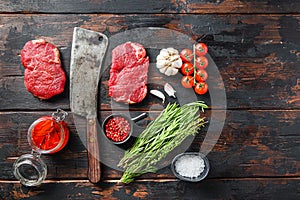 Rumpsteak organic meat cut, raw marbled beef steak, with old butcher knife cleaver, and seasonings  On dark wooden rustic table,