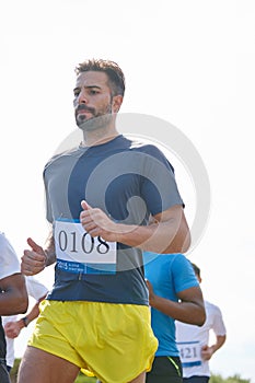 Run your own race. a young man running a marathon with other runners in the background.