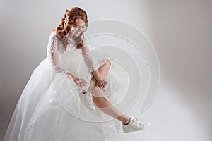 Runaway bride laces shoelaces. girl in a magnificent wedding dress and white sneakers