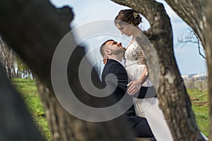 Private photo peeping from behind the bride and groom from the trees. Amorous couple on a natural background. In artistic creative