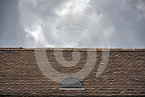 A rundown old roof made from terracotta tiles against a cloudy sky background, architectural details of an old building