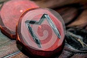Rune Ehwaz red color carved from wood on a wooden background