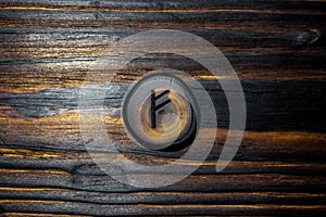Rune Fehu carved from wood on a wooden background photo