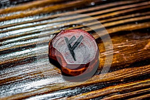 Rune Fehu red color carved from wood on a wooden background