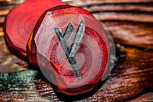 Rune Fehu red color carved from wood on a wooden background