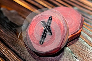 Rune Naudiz red color carved from wood on a wooden background