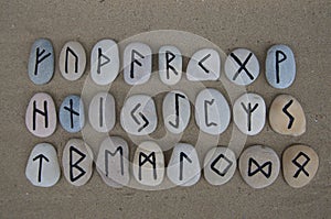 Runic alphabet on carved stones over the sand photo