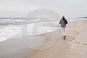 Runner athlete man running in autumn fall by the water jogging by water