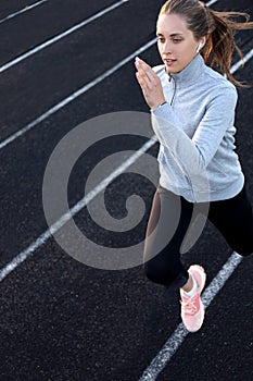 Runner athlete running on athletic track training her cardio in stadium. Jogging at fast pace for competition